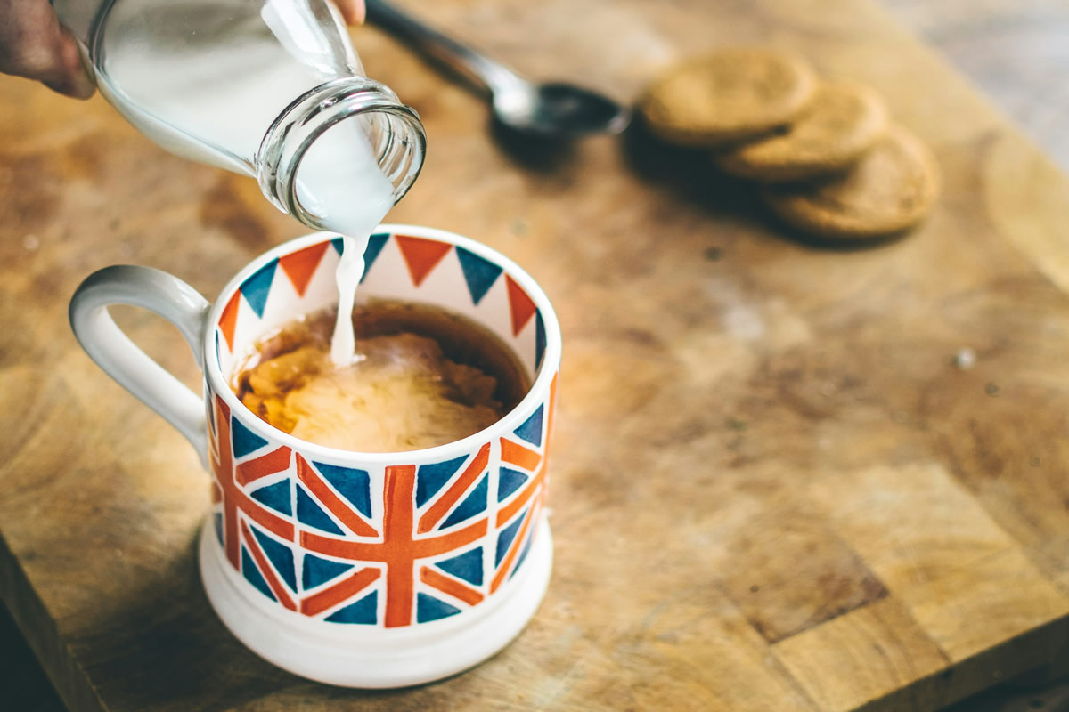 Pouring milk into a mug with coffee for your daily routine.